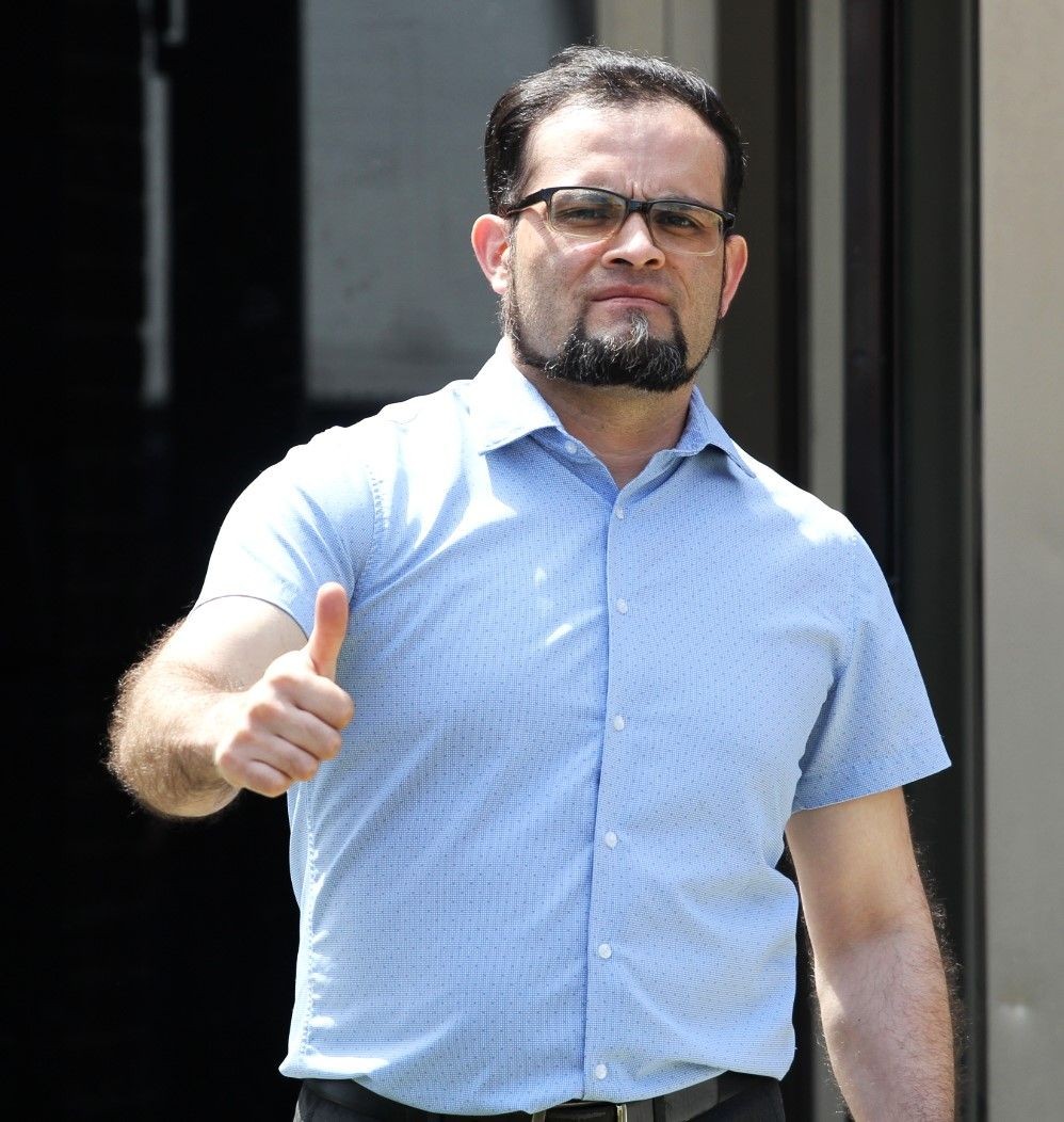 Man wearing a light blue short-sleeve shirt giving a thumbs-up gesture.